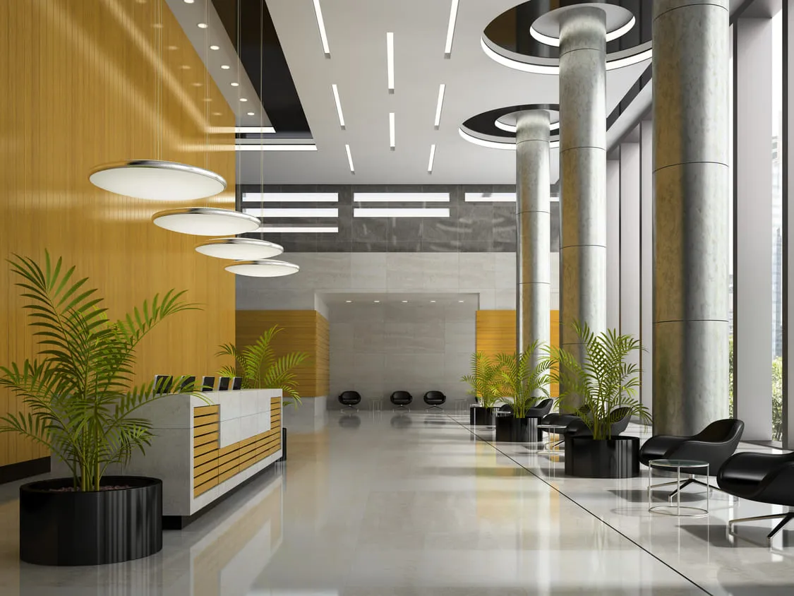 Modern commercial office lobby with reception desk, plants, and contemporary lighting